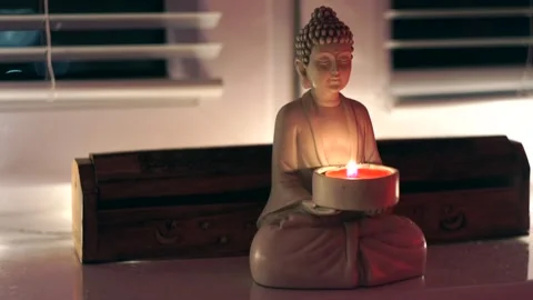 Buddha Statue on a windowsill, fired candle, peace and calm meditation time Stock Footage 183066366
