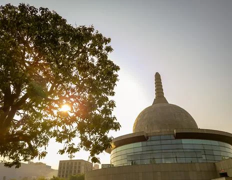 Buddha stupa through leafs with bright sky at morning from low angle Foto stock