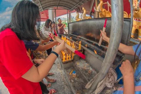 Buddhist devotee lighting a stick with a candle at Hat Yai Municipal Park. Stock Photos