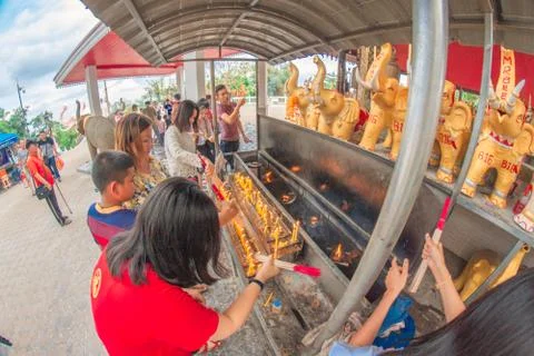 Buddhist devotee lighting a stick with a candle at Hat Yai Municipal Park. Stock Photos