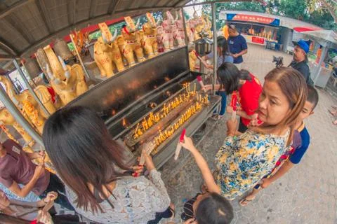 Buddhist devotee lighting a stick with a candle at Hat Yai Municipal Park. Stock Photos