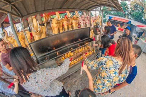 Buddhist devotee lighting a stick with a candle at Hat Yai Municipal Park. Stock Photos