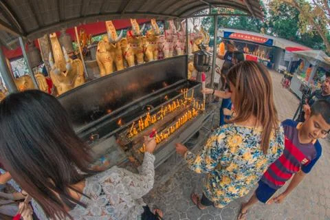 Buddhist devotee lighting a stick with a candle at Hat Yai Municipal Park. Stock Photos