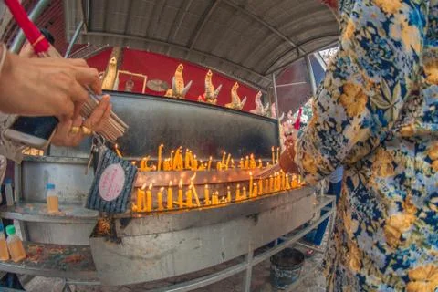 Buddhist devotee lighting a stick with a candle at Hat Yai Municipal Park. Stock Photos
