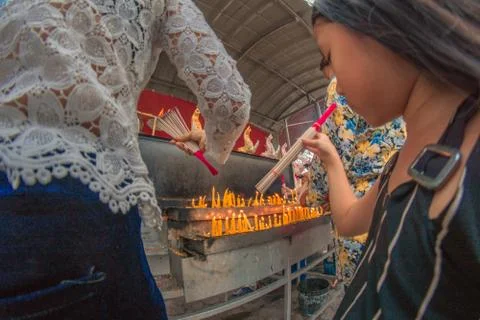 Buddhist devotee lighting a stick with a candle at Hat Yai Municipal Park. Stock Photos