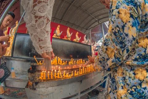 Buddhist devotee lighting a stick with a candle at Hat Yai Municipal Park. Stock Photos