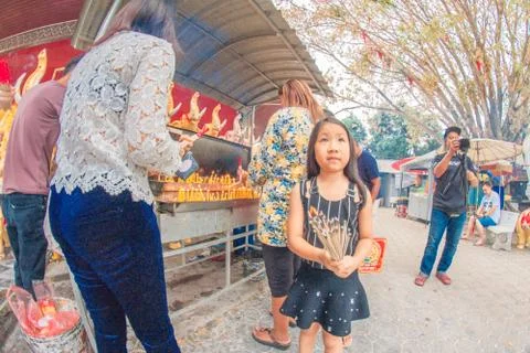 Buddhist devotee lighting a stick with a candle at Hat Yai Municipal Park. Stock Photos