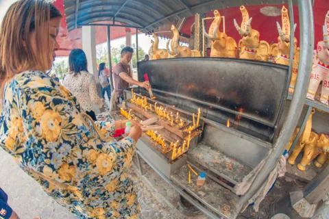 Buddhist devotee lighting a stick with a candle at Hat Yai Municipal Park. Stock Photos