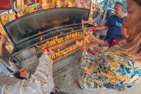 Buddhist devotee lighting a stick with a candle at Hat Yai Municipal Park. Stock Photos