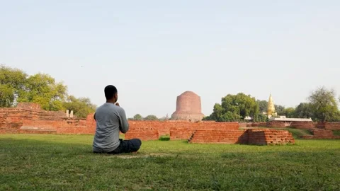 Buddhist devotee performing sacred meditation at dhamek stupa ruins in day Stock Footage 315727183