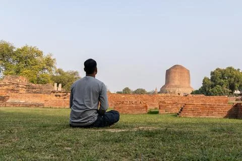Buddhist devotee performing sacred meditation at dhamek stupa ruins in day .. Foto stock
