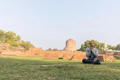 Buddhist devotee performing sacred meditation at dhamek stupa ruins in day .. 스톡 사진