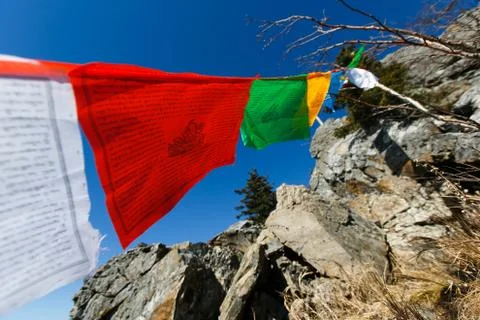 Buddhist flags with prayers and mantras develop on top of the mountain. Stock Photos
