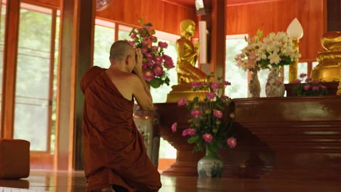 Buddhist monk bows in front of Buddha statue in temple Stock Footage 218572042