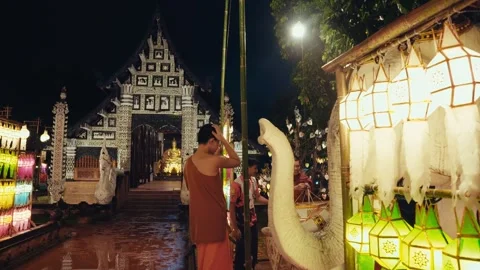 Buddhist monk installing decoration at temple gate with colorful lanterns Stock Footage 332511988