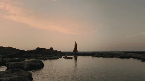 Buddhist monk in red robes on the beach after sunset Stock Footage 274947457