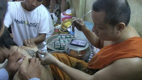 Buddhist monk tattooing a man Stock Footage 103451017