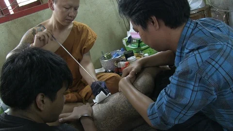 Buddhist monk tattooing a man Stock Footage 103451275