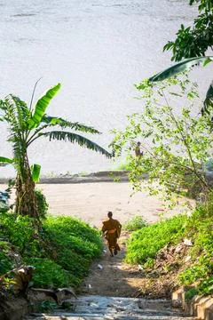 Buddhist monk walking down path to mekong river Stock Photos