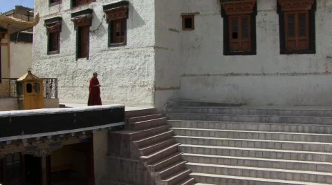 Buddhist monk walks down steps in monastery Stock Footage 235186