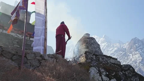 Buddhist monkburn a fire outside temple. Smoke move up. Snow mountains backdrop Stock Footage 167418656