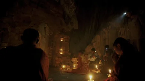 Buddhist monks praying inside a candlelit sacred cave 库存影片 331952986