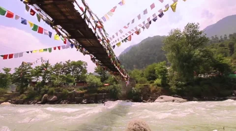 Buddhist prayer flags, fast flowing river and traditional bridge. Still shot. Stock Footage 66525584
