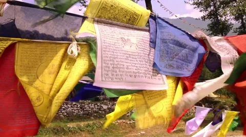 Buddhist prayer flags flapping in wind, close up, pan to fast flowing river Stock Footage 66525586
