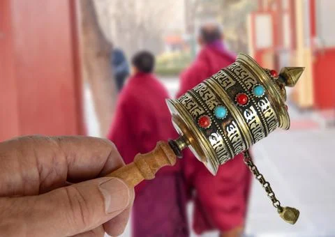 Buddhist Prayer Wheel in front of two Buddhist monks Stock Photos
