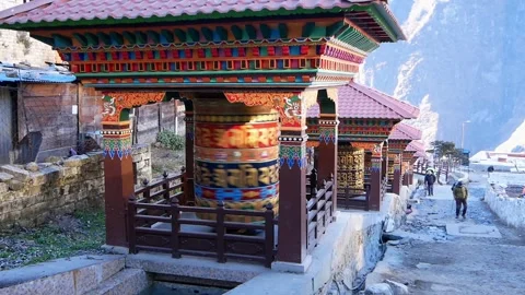 Buddhist prayer wheel powered by flowing water with trekkers passing by in Nepal Stock Footage 146120947