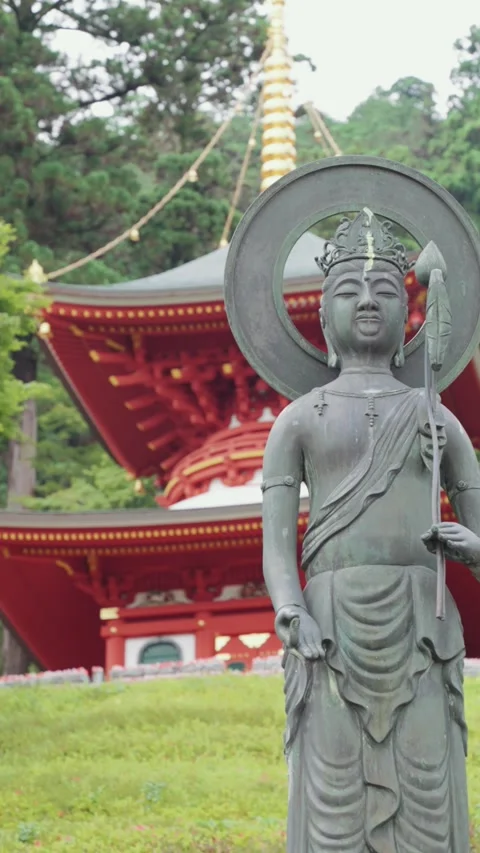 Buddhist statue stands peacefully in front of the vibrant red temple Stock Footage 345740954