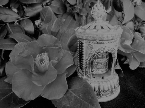 Buddist Tibetan prayer wheel Mani wheel and flowers in a grey scale Stock Photos