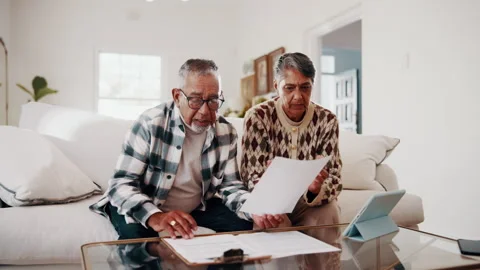 Budget, documents and tablet with old couple in home living room for finance or Stock Footage 338395287
