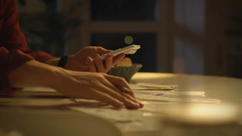 Budgeting at home through expense tracking using a smartphone in the evening Stock Footage 323731834