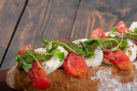 Buffalo mozzarella bruschetta with tomato and pesto on rustic background Stock Photos