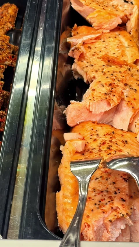 Buffet display featuring seasoned fish and sliced salmon served with metal tongs Vidéo 348900518