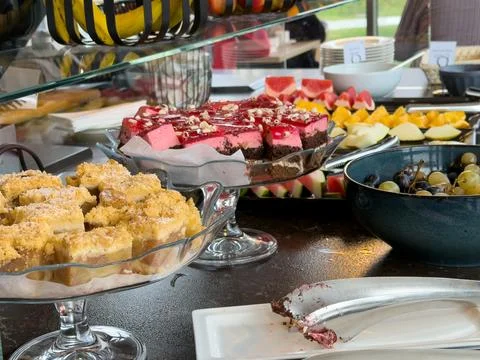 A buffet spread featuring fresh fruit and sweet cakes on glass stands, Stock Photos