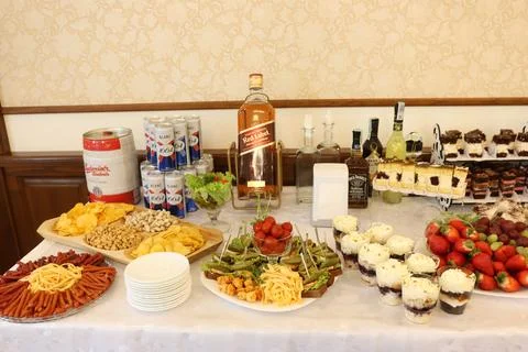 Buffet table with alcoholic drinks, snacks, cakes and fruit. Stock Photos