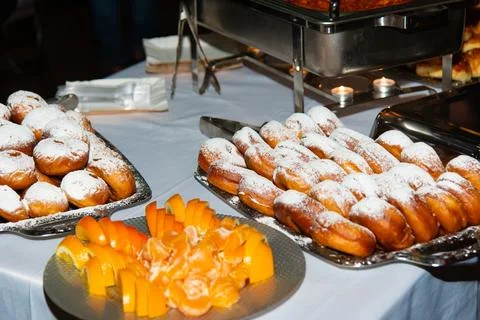 Buffet table full of assorted food, featuring powdered sugar covered donuts Stock Photos