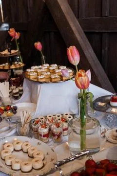 Buffet table with pastries in rustic barn setting featuring pink tulips in glass Stock Photos
