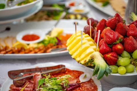 Buffet table of reception with cold snacks, salads and fruits Stock Photos