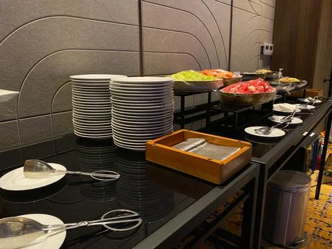 Buffet table setting in hotel or restaurant. Stack of plates, pile of spoon.. Stock Photos