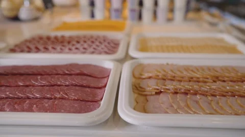 Buffet table with sliced deli meats and cheeses arranged in white trays Stock Footage 341166295