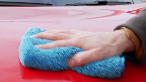 Buffing a glossy red hood with a soft blue microfiber cloth - close up Stock Footage 321037030
