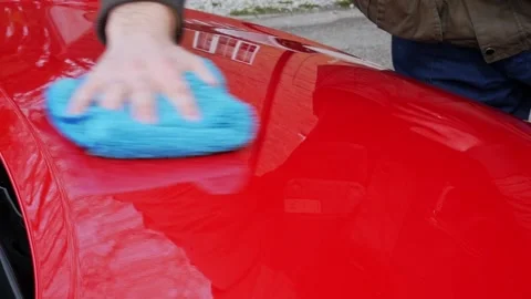 Buffing a glossy red hood with a soft blue microfiber cloth Stock Footage 321037033