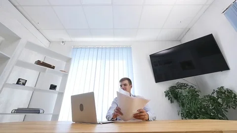 Bug eye. Young businessman is reading paperwork at desk in office. He throws Stock Footage 124661544