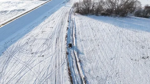 Buggy riding at snow-covered field road in rural environment. Follow to ATV Vidéo 335883807