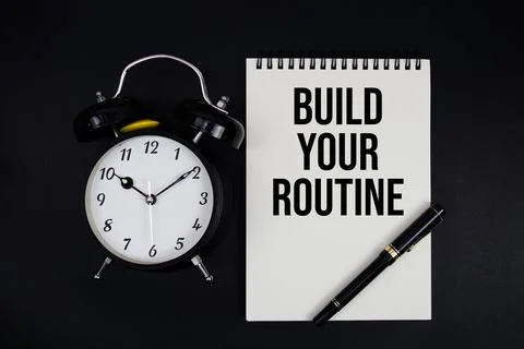 Build Your Routine text written on notepad with alarm clock top view on bla.. Stock Photos