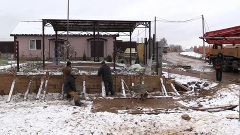 Builder align concrete retaining wall in wooden formwork on winter country side Stock Footage 83498855