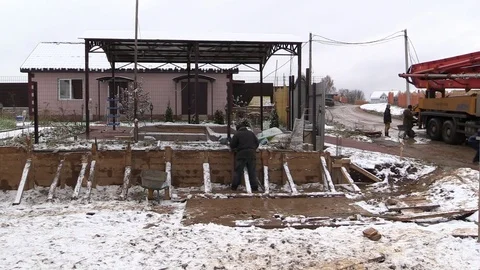 Builder align concrete retaining wall in wooden formwork on winter country side Stock Footage 83498858